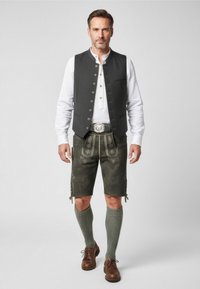 Grå väst över vit skjorta, mörka shorts med broderi, gröna knästrumpor och bruna skor. Har detaljerade accenter och knappar.
