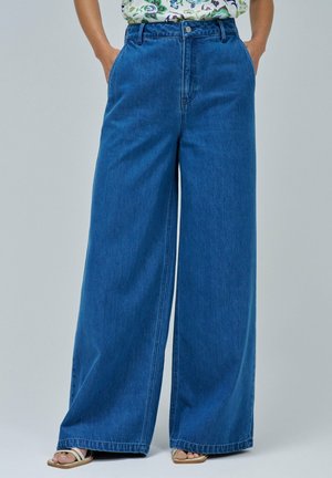 Jeans de mezclilla de pierna ancha en azul medio, con una cintura alta, bolsillos y una textura suave. Acabados con un botón metálico y cremallera.