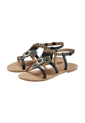 Black flat sandals with decorative beaded accents, featuring multiple straps, a cushioned beige insole, and adjustable ankle buckle.