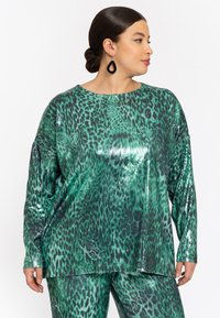 Grüner Pailletten-Top mit einem Leopardenmuster, langen Ärmeln und einer lockeren Passform. Glatte Textur mit reflektierenden Oberflächenakzenten.