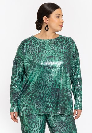 Top en sequins verts avec un motif léopard, à manches longues et à coupe décontractée. Texture lisse avec des accents de surface réfléchissants.