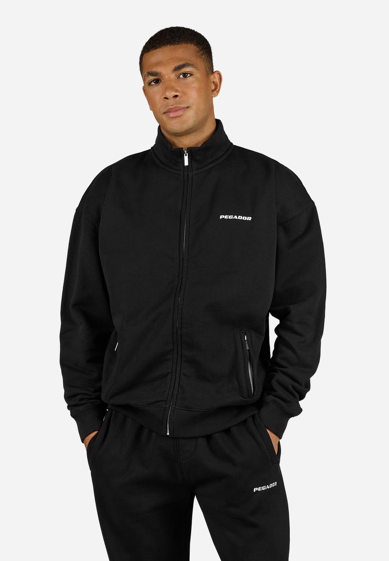 Zwarte ritssluiting sweatshirt van katoen. Heeft een hoge kraag, zijzakken en een wit "PEGADOR" logo op de borst. Gestyled met bijpassende broek.