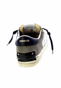 Vista posteriore di una sneaker grigia e bianca con tallone nero e lacci scuri, con logo "CRIME" sul tab del tallone.