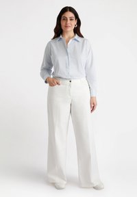 Camicia button-up a righe blu chiaro con maniche lunghe, abbinata a pantaloni bianchi a gamba larga, dotati di tasca frontale e una texture liscia.