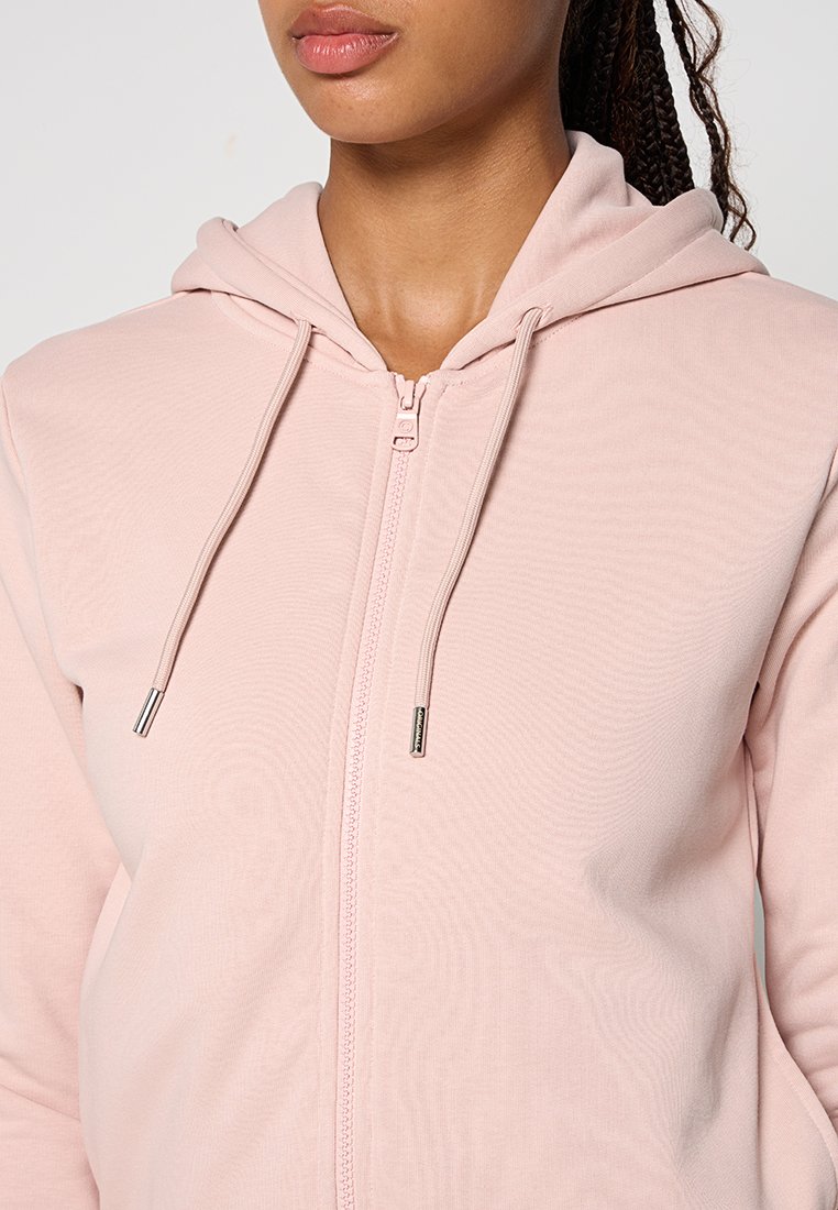 Felpa con zip di colore rosa chiaro, dotata di cappuccio regolabile con lacci, dalla texture liscia e con accessori in metallo argento sulla cerniera. Design semplice senza pattern.
