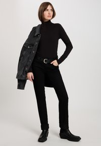 Czarny golf połączony z czarnymi jeansami o slim-fit i szarym dżinsowym kurtką. Czarny pasek z srebrną klamrą oraz czarne botki za kostkę.