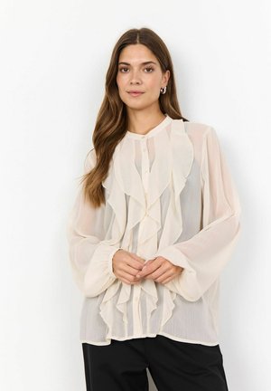 Light beige blouse with ruffled front and high neckline. Long, billowing sleeves and button closure at the front, made of sheer fabric.