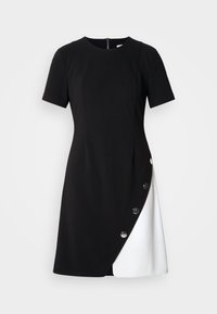 Vestido preto e branco de manga curta com silhueta ajustada, apresentando um fecho de correr nas costas e botões grandes ao longo da costura lateral.