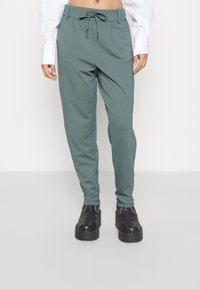 Gröna, avsmalnande sweatpants med elastisk midja och dragsko. Mjukt tyg med sidofickor, kombinerat med svarta plattformsskor.