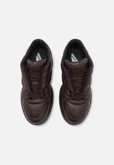 Brown leather sneakers with a high-top design, featuring laces, padded collar, and a smooth texture. Rounded toe and cushioned sole.