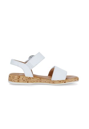 White open-toe sandal with cork-patterned sole, adjustable ankle strap, and wide front strap on a white background.