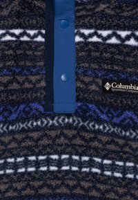 Pullover in pile con texture a motivi marrone scuro, blu e bianco. Presenta una patta abbottonata blu e un'etichetta con il logo Columbia.