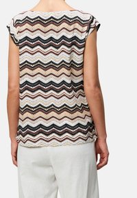 Haut à manches courtes avec un motif en chevrons beige, marron et noir. Confectionné en tissu léger avec une coupe décontractée.