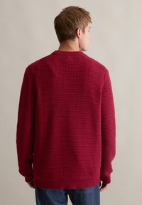 Roter strukturierten Strickpullover mit geripptem Rundhalsausschnitt und Bündchen. Hat eine lockere Passform und ist aus einem weichen, warmen Stoff gefertigt.
