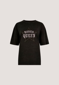 Camiseta de algodón negra con mangas cortas, que presenta un gráfico de "REINA DEL RODEO" en blanco y tachuelas metálicas doradas, con un diseño de estrellas como acento.