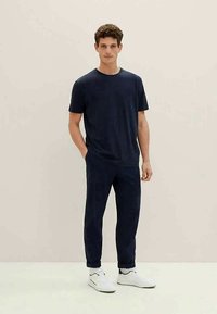 Marineblå bomulls-t-skjorte med korte ermer og rund hals, kombinert med marineblå joggebukser og hvite joggesko. Enkel, avslappet passform.