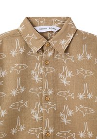 Camicia corta a maniche corte color beige con motivo di pesci bianchi e palme, colletto button-down e bottoni di legno, realizzata in tessuto di lino.