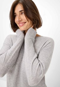 Hellgrauer Pullover aus weichem Material, mit einem weiten Ausschnitt, langen Ärmeln und gerippten Bündchen, in einem entspannten Schnitt, der angenehm fällt.
