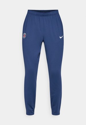 Navy athletic pants made from smooth fabric, featuring an elastic waistband, Nike logo in white, and a Paris Saint-Germain emblem on the thigh.