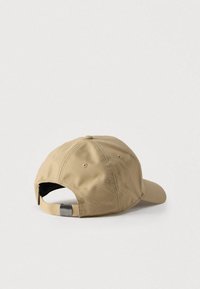 Μπεζ καπέλο μπέιζμπολ με υφή υφάσματος, καμπυλωτή γείσο και ρυθμιζόμενο πίσω ιμάντα με μεταλλικό κούμπωμα.