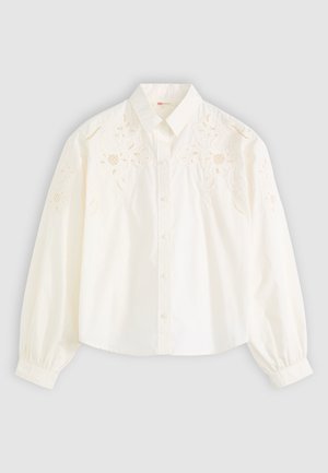 Blusa bianca in cotone con maniche lunghe a palloncino, caratterizzata da un'elegante ricamatura floreale sulle spalle, colletto classico e chiusura con bottoni davanti.