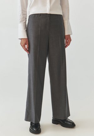 Gray tailored trousers with a wide-leg design, featuring a subtle texture and pleats. Worn with black platform shoes and a white shirt.