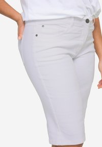 Shorts bermuda en denim blanc avec un design ajusté, taille mi-haute, poches avant et accents en métal. Texture lisse sur toute la surface.
