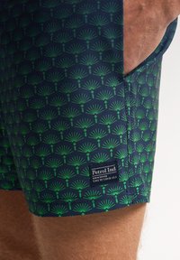 Pantaloni da bagno navy con un motivo a foglia di palma verde, dotati di una tasca integrata e di un etichetta con il marchio "Petrol Ind."