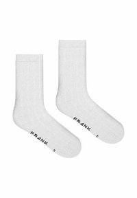 Vita bomullsstrumpor med en mjuk textur, utrustade med en ribbad mudd och ordet "FRANK" tryckt i svart nära tån.