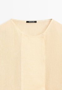 Hellbeiger gestrickter Pullover mit rundem Halsausschnitt und einem innen im Kragen eingenähten Massimo Dutti Etikett.