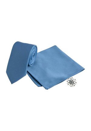 Rolled light blue necktie, matching pocket square, and silver starburst lapel pin arranged on white background.