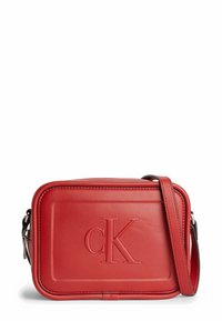 Bolso bandolera de cuero rojo con logo "cK" en relieve, forma rectangular, textura suave y correa ajustable. Presenta acentos de costura.