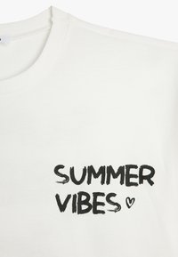 Weißes Baumwoll-T-Shirt mit Rundhalsausschnitt. Frontaufdruck in fettem Schwarz: "SUMMER VIBES" mit einem kleinen Herzakzent. Glatte Textur.