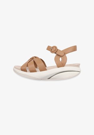 Sandale en cuir tan avec lanières avant nouées, bride de cheville ajustable avec boucle ronde, et semelle épaisse blanche rembourrée avec détail de voûte plantaire.