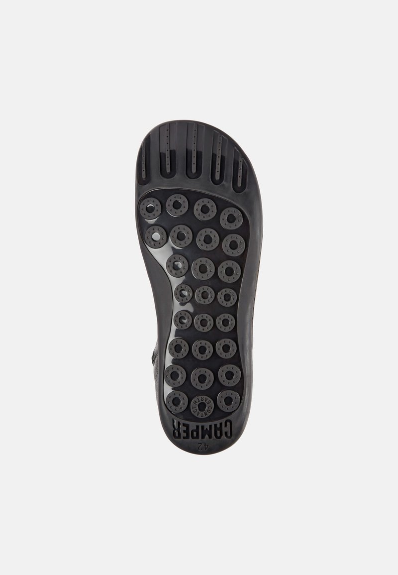 Black rubber sole with a textured surface, featuring circular grips, vertical ridges, and the brand name "Camper" visibly embossed.