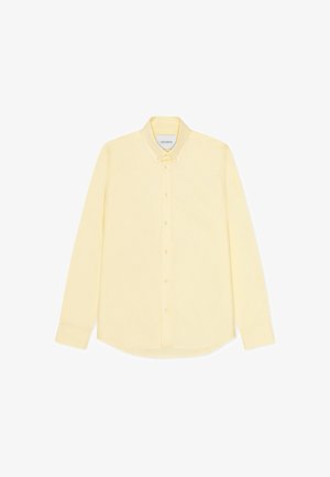 Żółta koszula na długi rękaw z guzikiem, z kołnierzykiem w szpic, zapinana na guziki z przodu, z zaokrąglonym dołem. Wykonana z lekkiego materiału.