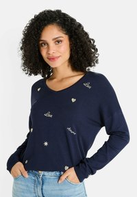 Suéter azul marino con escote en V, que presenta texto bordado en oro que dice "Amor" y corazones, mangas largas y un corte relajado.