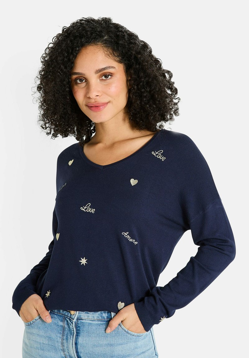 Suéter azul marino con escote en V, que presenta texto bordado en oro que dice "Amor" y corazones, mangas largas y un corte relajado.