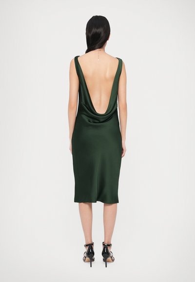 Zielona sukienka z satyny z głębokim dekoltem na plecach w kształcie litery V, bez rękawów i dopasowanym fasonem. Charakteryzuje się gładką fakturą i sięga do połowy łydki.