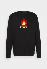 Czarny długi rękaw sweatshirt z kolorowym wzorem ogniska przedstawiającym kłody drewna i czerwono-żółte płomienie umieszczonymi na środku klatki piersiowej.