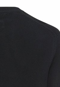 Czarny sweter o fakturze dzianiny, z prążkowanym okrągłym dekoltem, wyraźnymi szwami na ramionach i gładkim wykończeniem.