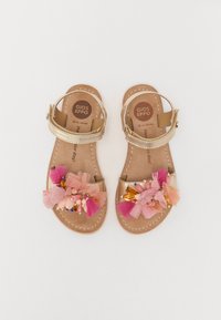 Sandales en cuir doré avec des embellissements en tulle rose et pêche, présentant des perles décoratives et une sangle à boucle. Semelle plate et design ouvert.