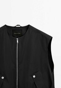 Veste noire sans manches avec fermeture éclair frontale et poches à rabat à bouton-pression, encolure ronde et boucle en tissu au col.