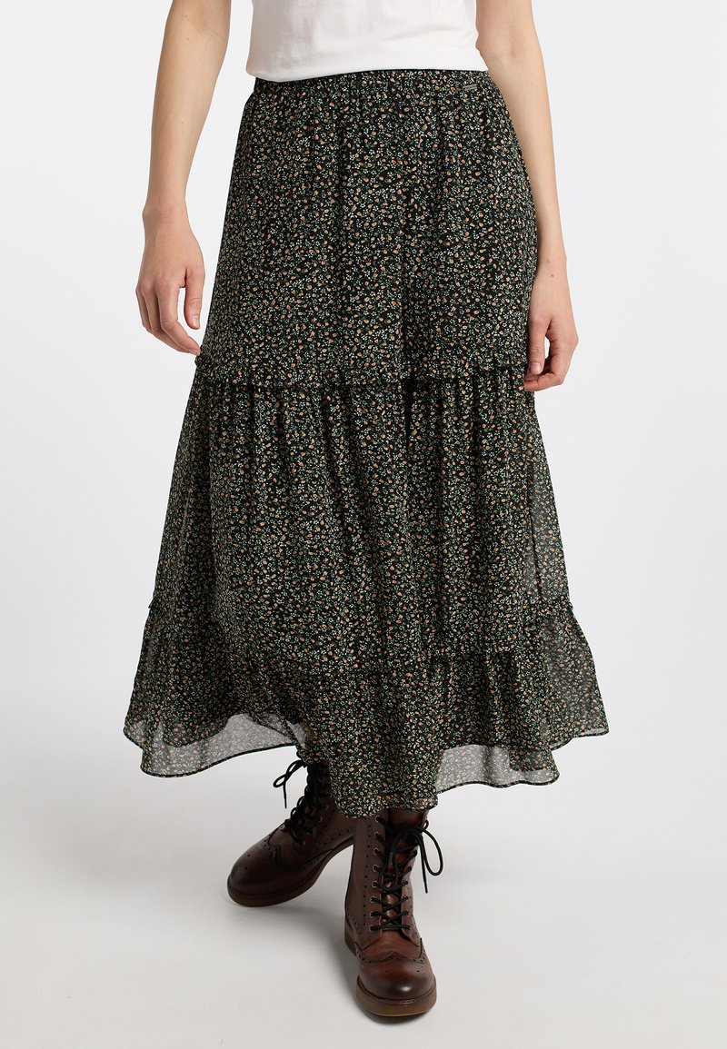 Schwarzer Maxirock mit floralen Mustern und gestuften Rüschenseiten, aus leichtem Stoff mit einem taillierten Taillenbund, kombiniert mit braunen Schnürstiefeln.