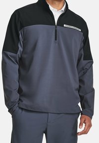 Grå og sort kvart-zip trøje lavet af glat stof, med en høj krave og et Under Armour-logo på brystet.