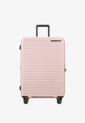 Pink hard-shell suitcase with horizontal ridges, a retractable black handle, four black wheels, and a side zipper.