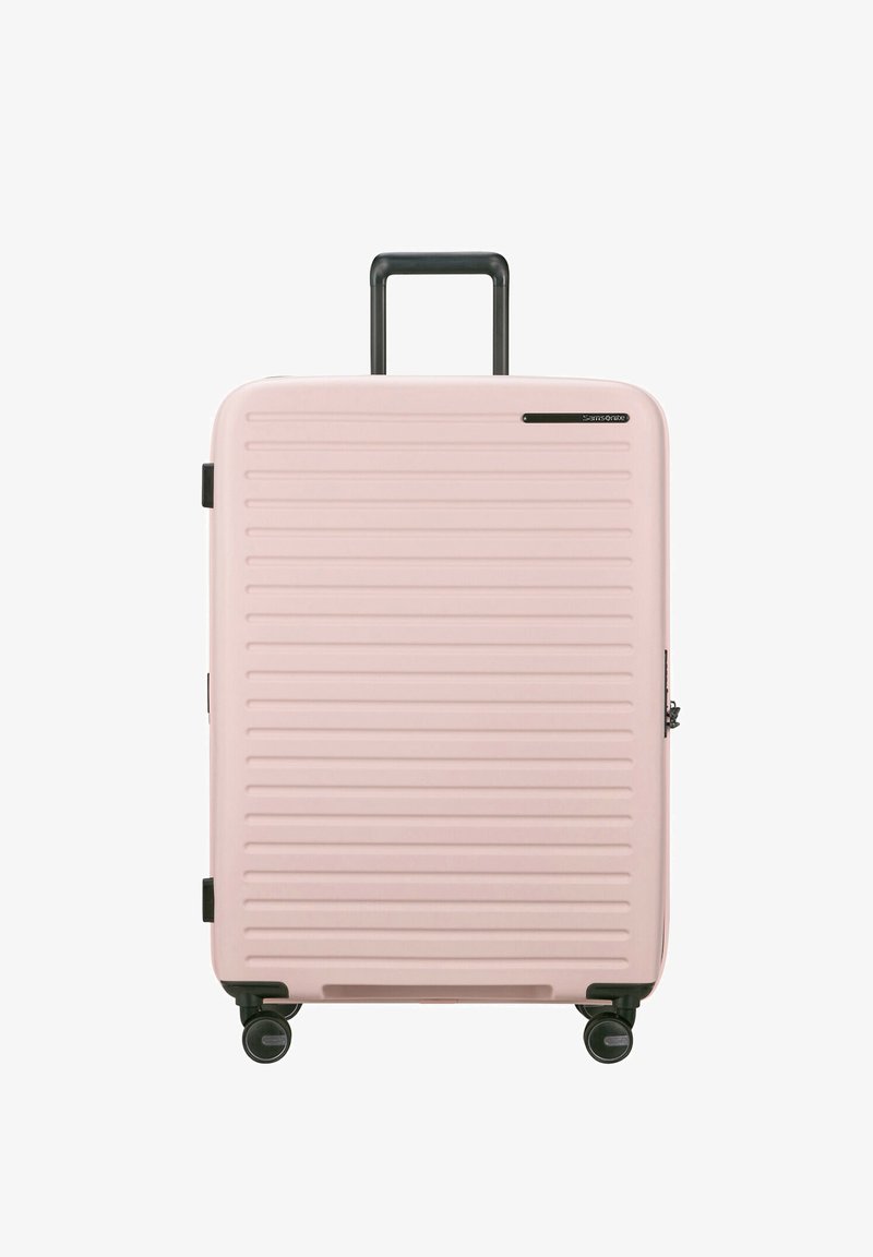 Rosa hartschalige Reisetasche mit horizontalen Rillen, einem ausziehbaren schwarzen Griff, vier schwarzen Rädern und einem seitlichen Reißverschluss.