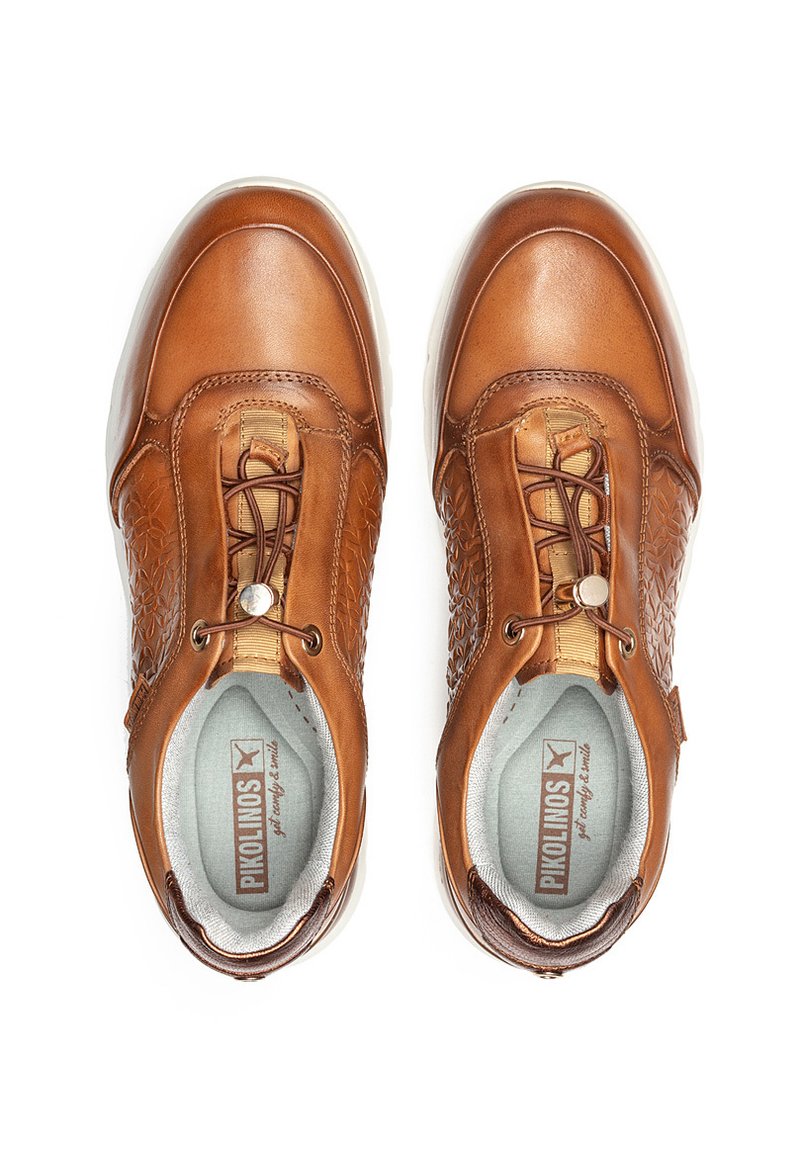 Zapatos de cuero marrón con lados texturizados, cordones elásticos y acentos de hardware redondeados. El interior tiene un forro de color gris claro y un logo.