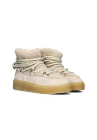 Beige suède laarzen met fluffy shearling manchetten, elastische veters en textuur rubberen zolen. Voorzien van een ronde neus en een laag profiel ontwerp.