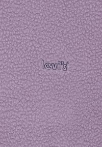 Fioletowy polar o teksturowanej powierzchni z haftowanym logo "Levi's" w ciemnoniebieskim kolorze.